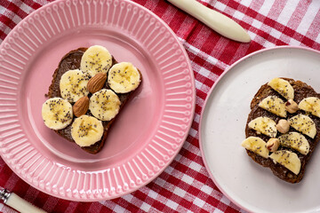 Toasted whole wheat bread with chocolate nuts paste nutella topping, banana, chia seeds, almonds and hazelnuts toast. Healthy proper nutrition for breakfast