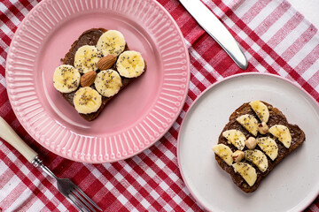 Toasted whole wheat bread with chocolate nuts paste nutella topping, banana, chia seeds, almonds and hazelnuts toast. Healthy proper nutrition for breakfast