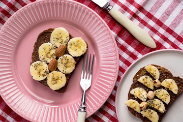 Toasted whole wheat bread with chocolate nuts paste nutella topping, banana, chia seeds, almonds and hazelnuts toast. Healthy proper nutrition for breakfast
