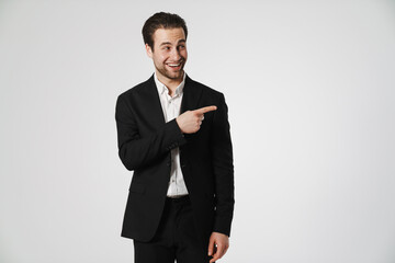 Unshaven brunette man in jacket smiling and pointing finger aside