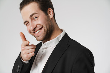 Unshaven brunette man in jacket winking and pointing finger at camera