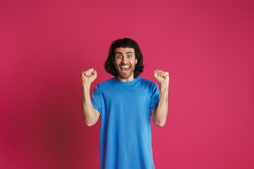 Excited brunette man holding clenched fists and looking at camera