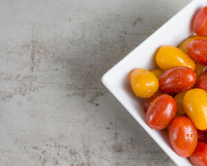 red and yellow small tomatoes in white square bowl. Flat lay 