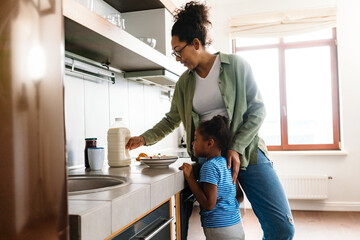 Happy mother preparing breakfast with her daughter in home kitchen
