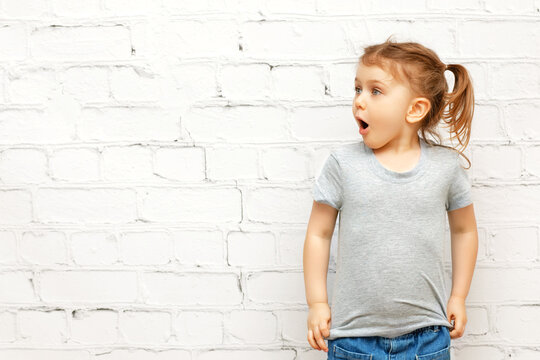 Excited funny child with expression face in casual clothes over background and looking at copy space. Concept of advertising and promoting goods,seasonal sale,discount, shopping, information and news