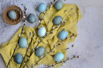 Festive Easter composition. Flat mockup of gray eggs, yellow napkin and willow branches on gray background. Happy Easter greeting card