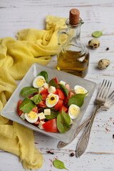 Light dietary salad with spinach and tomatoes on a yellow napkin on a light rustic background. Vertical