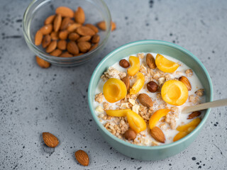 Delicious and healthy food for breakfast. Muesli with milk, pieces of apricot fruit, hazelnuts and almonds
