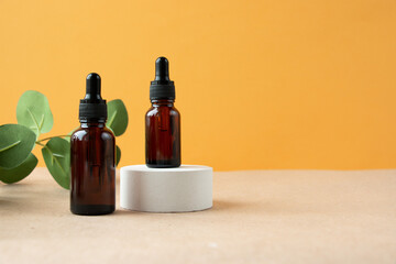 A cosmetic bottle with an amber glass dropper sits on a concrete pedestal. Natural beauty products. Mineral organic oil. Empty bottle for skin care. Hard sunlight.