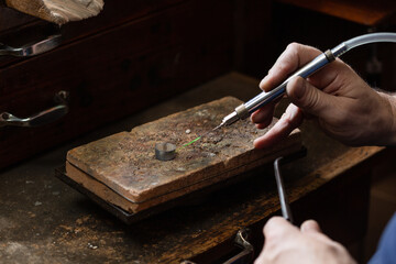 goldsmith jeweler soldering a silver ring on the workbench with a soldering.