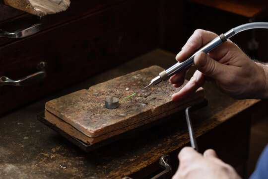 goldsmith jeweler soldering a silver ring on the workbench with a soldering.