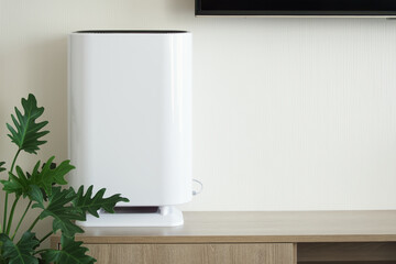 Air purifier and Hepa filter system placed on wooden cabinet, Backdrop of white wall with copy space, Living room and furniture decorated in minimalist style, Home electric appliances and Health care.