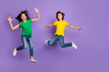 Full body photo of two young kids happy positive smile have fun jump up isolated over violet color...