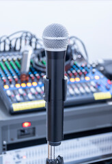 The microphone on tripod in the center of the image with mixer background in sound control