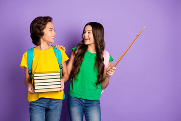 Photo of two happy children girl point stick boy hold books school wear casual outfit copyspace isolated on purple color background