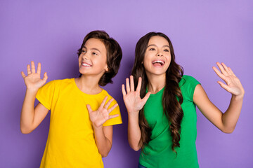 Photo of two excited kids happy positive smile have fun show hands look empty space isolated over violet color background