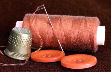 the spool of thread and the needle are on the table
