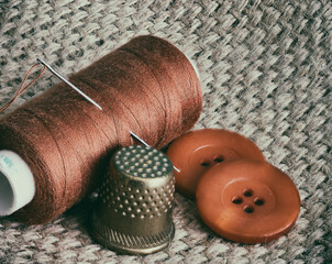 the spool of thread and the needle are on the table