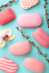 Different pink soaps with flowers. A lot of solid soap for hygiene and cleanliness on a blue background.