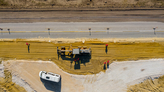 Aerial view on grader as leveling sand over construction site for new traffic roundabout