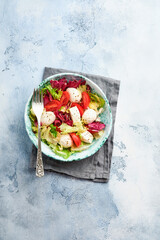 Mozzarella, tomato and mix of fresh salad leaves, slate stone table background, top view. Mock up.
