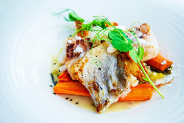 Delicious fillet of cod fish with carrots, leeks and mushrooms in white plate ready to be served