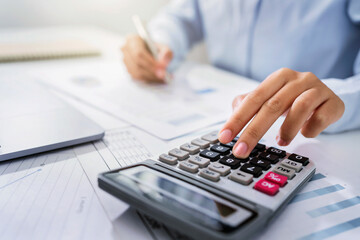 Woman accountant use calculator and computer with holding pen on desk in office. finance and...