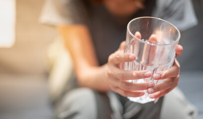 Female hand holding empty glass and sitting on the sofa in liveing room