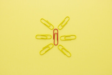 Design to yellow clip blocking around the red clip on yellow paper background. This creative shows the different ideas or paradoxical, and unique. different idea concept.