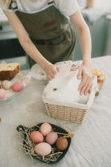 young beautiful girl holding an Easter bunny at a festive Easter table.