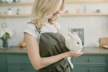young beautiful girl holding an Easter bunny at a festive Easter table.