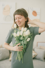 Beautiful happy girl holding a bouquet of tulips in her hands and smiling