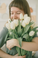 Beautiful happy girl holding a bouquet of tulips in her hands and smiling