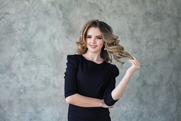 Fototapeta premium Happy pretty woman with curly hair touching her hair her hand