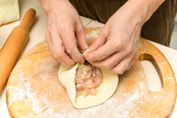 Close-up of female hands while cooking. A woman cooks meat pies.