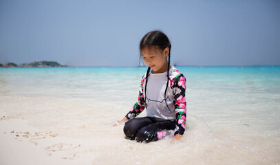 Young women in flower-patterned dresses sat in the sand at the seaside with the beautiful sky and the blue sea.