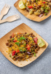 kala chana chaat with boiled potato, onion, tomato with lemon on a bamboo plate 