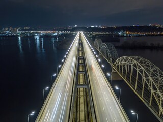 Naklejka premium Automobile and railway bridge in Kiev. Night illumination of the bridge. Aerial drone view.