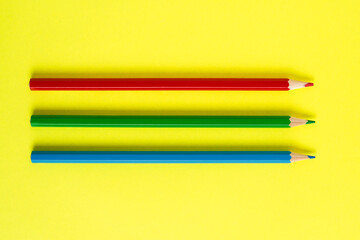 Red, green and blue pencils on a yellow background. RGB and CMYK color space concept.