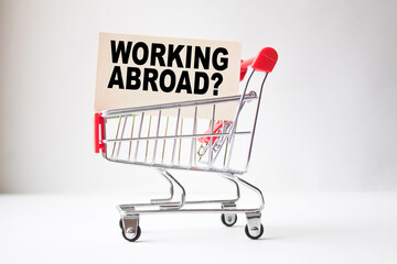 a business card with text WORKING ABROAD in a shopping cart. business and finance