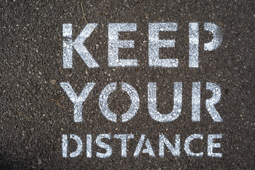 Keep Your Distance is written on the road amid COVID-19 pandemic to remind people to keep social distance