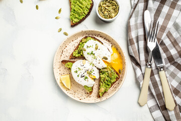 toasted bread with avocado and poached egg. Delicious breakfast or snack on a light background, top view