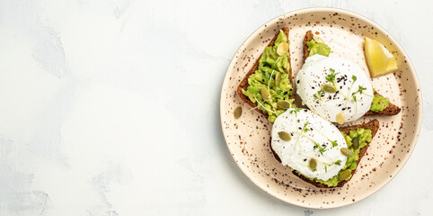 Fototapeta na wymiar toasted bread with avocado and poached egg. Delicious breakfast or snack on a light background. banner, menu recipe place for text, top view