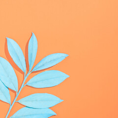 Fototapeta na wymiar Minimal retro tropical leaf flat lay idea. Exotic bright pastel blue leaves on orange background. Vibrant summer background concept with copyspace.