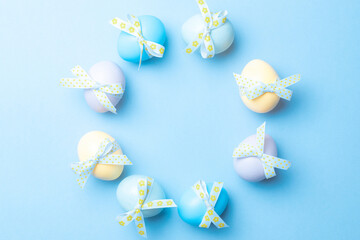 Easter flat. Colorful egg with tape ribbon on pastel blue background in Happy Easter decoration. Spring holiday top view concept.