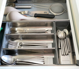 Spoons and forks in the kitchen drawer. Cutlery in a container for storing dishes. Set of kitchen utensils.