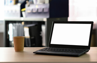 Fototapeta premium Cropped shot of Laptop blank screen with take away coffee on the table in office.