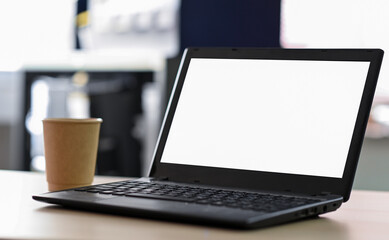 Cropped shot of Laptop blank screen with take away coffee on the table in office.