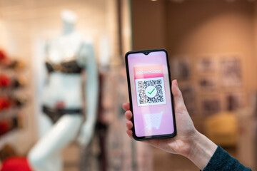 A woman's hand holds a cellphone with a qr code for a discount in the internet store. The concept of internet shopping