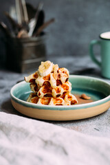 Belgian waffles with banana and honey on a turquoise plate